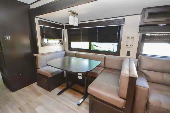 Inside this RV rental, discover a dinette with light grey U-shaped bench seating and a black table, ideal for travel meals.. Jayco Jay Flight 2022