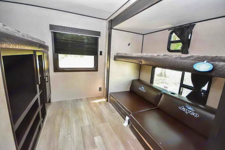 RV rental bunk room shows upper/lower bunks, convertible sofa, window, and storage cabinets.. Jayco Jay Flight 2022