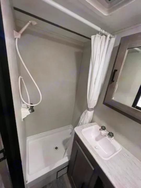 RV rental bathroom with a compact stand-up shower, handheld sprayer, and vanity featuring a sink and mirror.. Keystone RV Springdale 2021