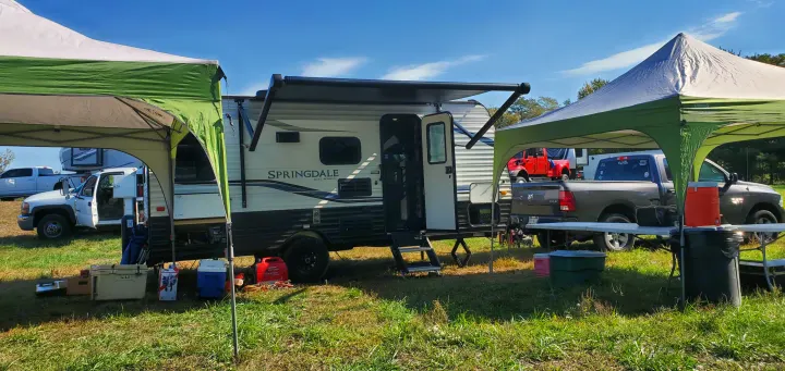 Perfect for camping, this RV rental setup boasts a Springdale travel trailer, two tents, trucks, and coolers.. Keystone RV Springdale 2021