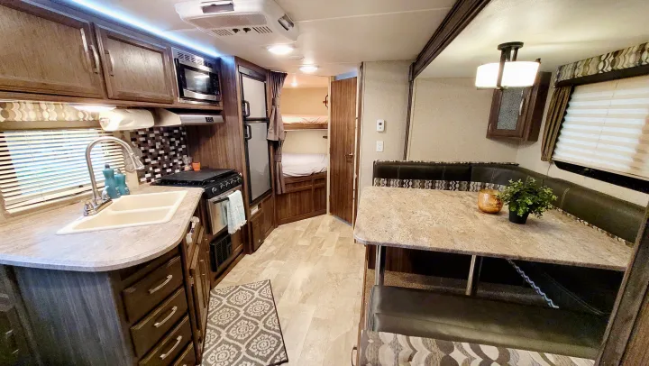 RV rental: Bright interior featuring a full kitchen with sink, stove, microwave, dinette, and bunk beds.. Coachmen Apex 2018