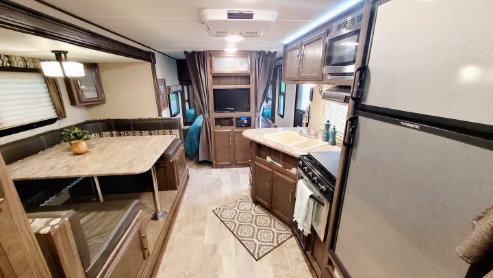 Spacious RV rental interior featuring a cozy dining nook, well-equipped kitchen with Dometic fridge, and entertainment center.. Coachmen Apex 2018