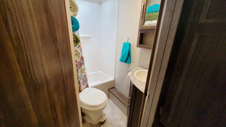 Compact RV rental bathroom with toilet, shower, and sink. Towels are stacked and hung, ready for your trip.. Coachmen Apex 2018