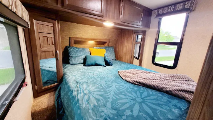 This RV rental's bedroom offers a comfy bed, ample storage, and natural light from large windows.. Coachmen Apex 2018