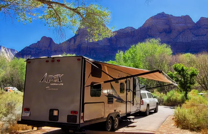 Enjoying a scenic RV rental trip, with an Apex Ultra Lite camper and SUV parked amidst majestic mountains.. Coachmen Apex 2018