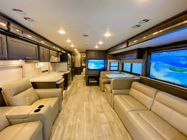 Spacious rv rental interior featuring a modern kitchen, comfy recliners, sofas, dining booth, & multiple TVs.. Thor Aria 2020