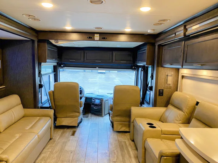 Inviting RV rental interior: spacious motorhome living area with comfortable seating, modern cockpit, and overhead storage.. Thor Aria 2020
