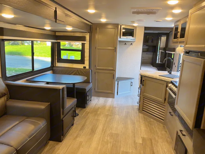 Spacious RV rental interior featuring a modern living area, dining booth, and fully equipped kitchen.. Jayco Jay Feather 2022