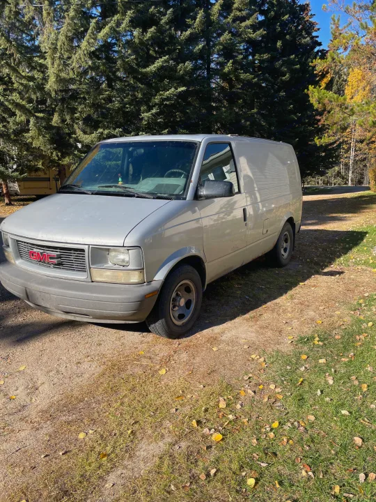 Silver GMC van parked in a wooded setting, near an RV. Explore RV rental possibilities!. Gmc Custom 1995