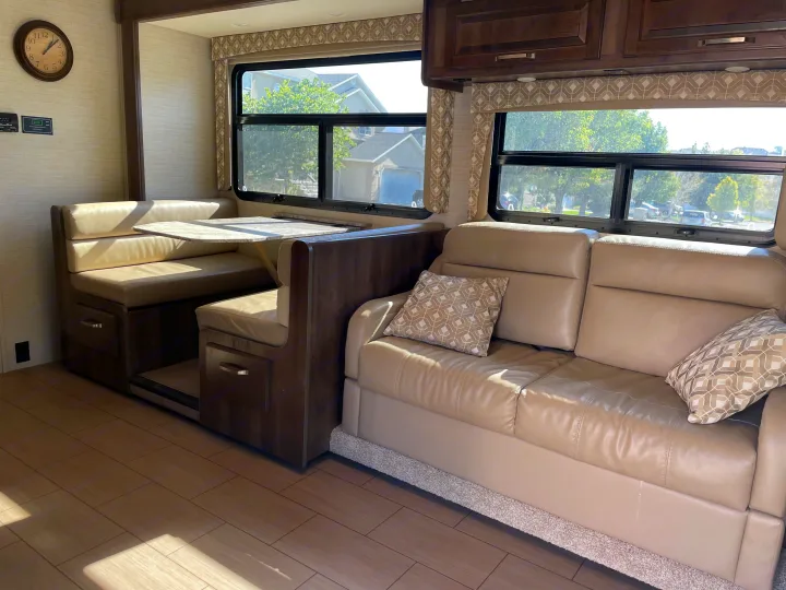 Comfortable RV rental interior featuring a beige dinette, sofa, and wood-look flooring for a cozy travel experience.. Jayco Greyhawk 2018