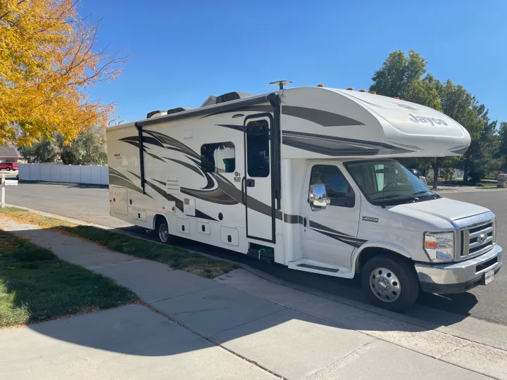 This white Jayco Class C RV rental is parked on a residential street on a sunny day, ready for adventure.. Jayco Greyhawk 2018