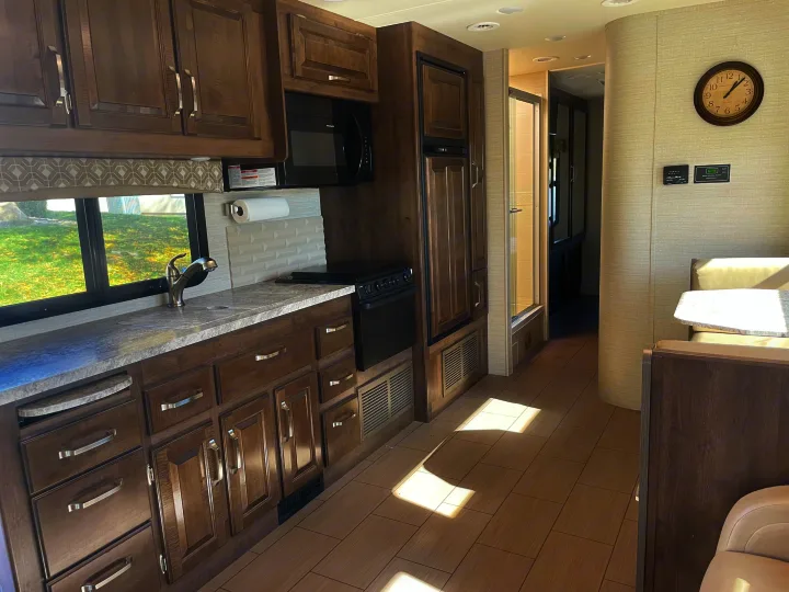 Modern rv rental interior with a well-appointed kitchen, including dark wood cabinetry, light counters, and a cozy dining booth.. Jayco Greyhawk 2018