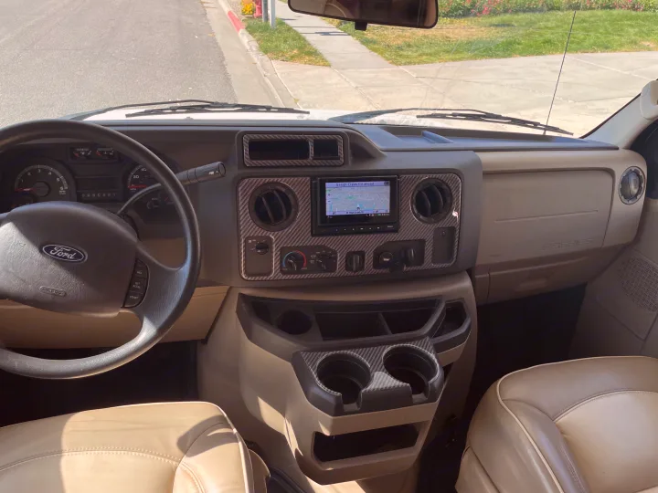 Dashboard view of an RV rental, featuring a Ford steering wheel, navigation screen, and detailed controls.. Jayco Greyhawk 2018