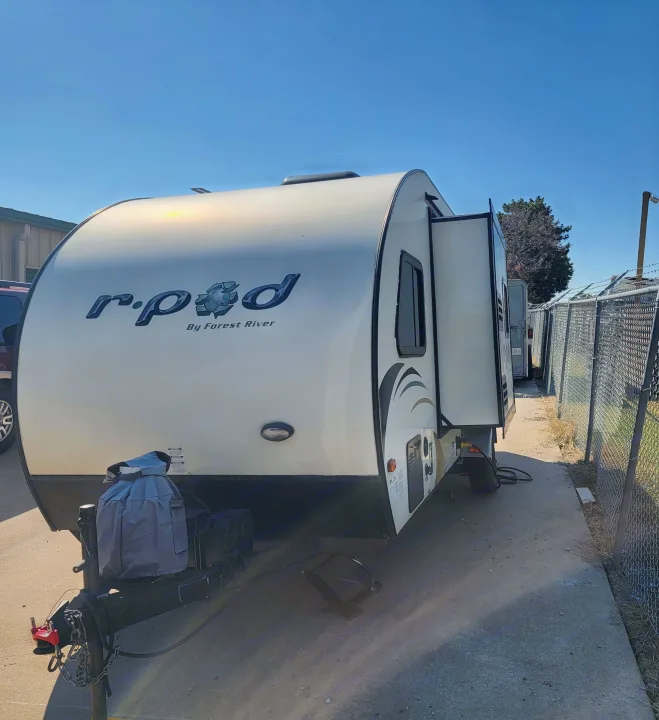 A light-colored r.pod travel trailer with an extended slide-out, parked outdoors, ideal for your next RV rental.. R-Pod R-Pod Trailer 2015