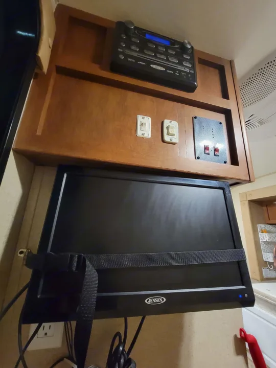 Inside an RV rental: Jensen TV secured by a strap, entertainment system, and control panel on wood cabinets.. R-Pod R-Pod Trailer 2015