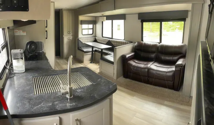 Bright & modern RV rental interior with kitchen, booth dinette, and plush sofa, ready for your road trip.. Forest River Tracer 2021