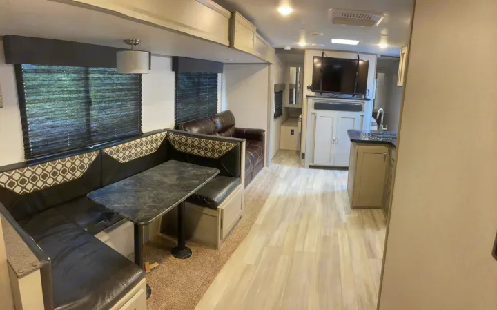 Spacious RV rental interior featuring a modern dinette, sofa, and kitchen. Perfect for adventures!. Forest River Tracer 2021