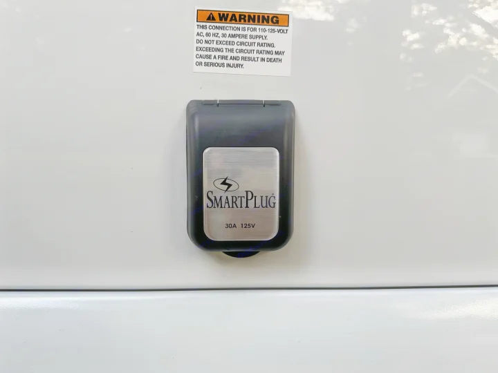 An RV rental's SmartPlug 30A 125V shore power inlet, featuring a crucial electrical warning label for safety.. Coachmen Other 2022