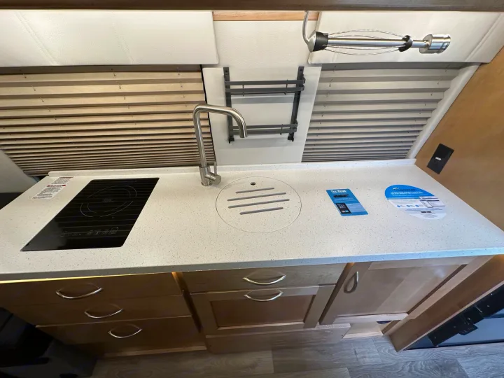 Explore this RV rental's modern kitchen: induction cooktop, faucet, sink, and ample cabinet storage.. Coachmen Other 2022