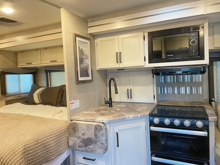 Spacious RV rental interior with kitchen, microwave, stove, sink, and a comfortable bedroom. Perfect for your next trip.. Thor Chateau 2022