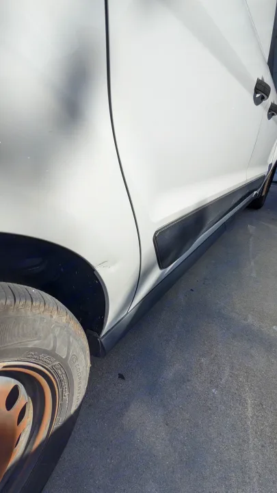 White RV rental van with a noticeable side body dent and scuff marks above the front tire.. Ford Transit Custom 2017