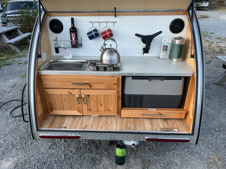 This RV rental's clever rear galley features a sink, stove, fridge, and storage, perfect for compact camping.. Little Guy Silver Shadow 2016