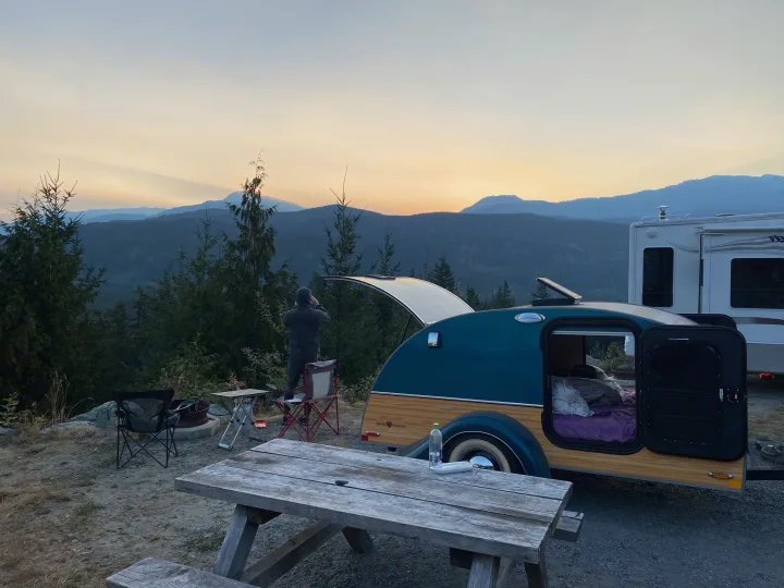 RV rental at a scenic mountain campsite with a teardrop camper, picnic table, and person watching sunset.. Little Guy Silver Shadow 2016