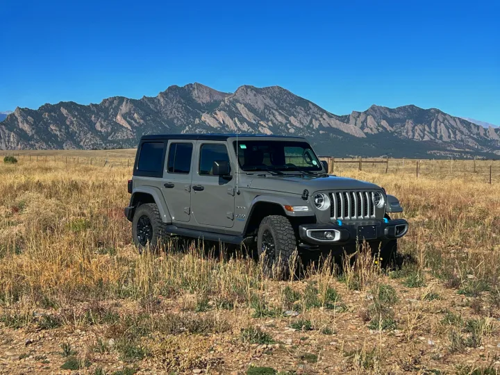 Grey Jeep Wrangler 4xe in a scenic mountain field, ideal for your next RV rental road trip.. Jeep Wrangler 2022