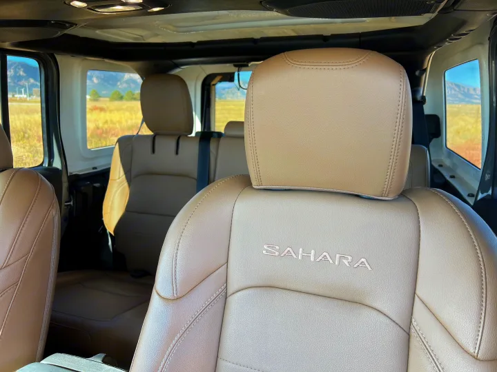 Jeep Sahara's tan leather interior, with embroidered logo, inviting for an rv rental road trip through scenic mountains.. Jeep Wrangler 2022