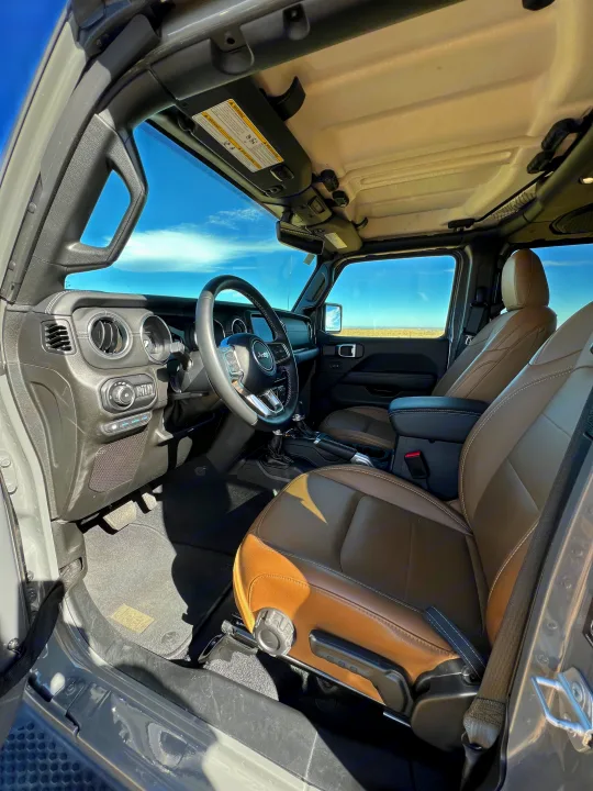 Open-air Jeep interior with rich brown leather seats and steering wheel, great for a scenic drive or an RV rental trip.. Jeep Wrangler 2022