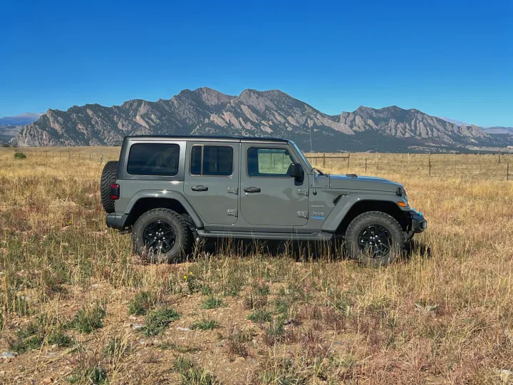 Gray Jeep Wrangler 4xe in a scenic field with mountains (likely Boulder Flatirons).. Jeep Wrangler 2022