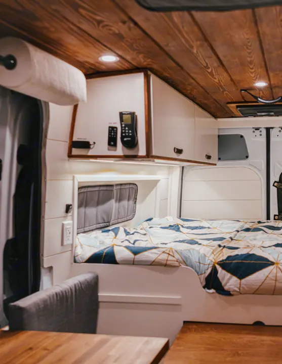Step into a cozy RV rental! This camper van interior features a comfy bed, wood ceiling, and smart storage for mobile living.. Mercedes-Benz Sprinter RV Motorhome Campervan 2022