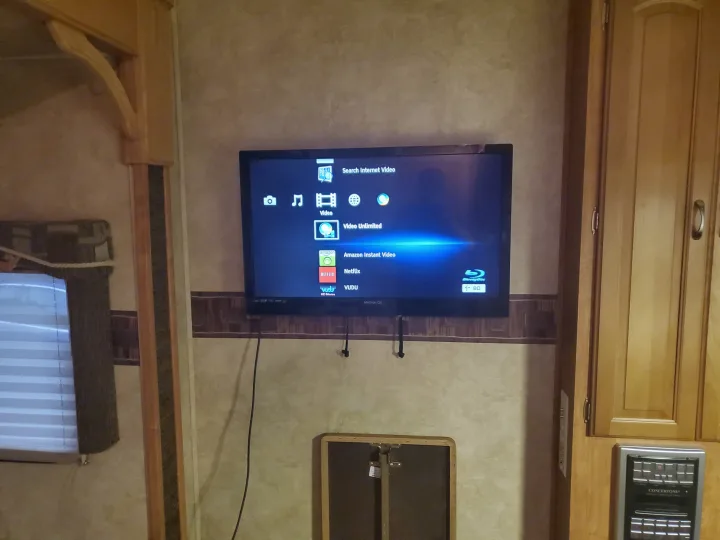 Inside an RV rental, a mounted TV shows streaming options (Netflix, Amazon, Vudu) for convenient entertainment on your travels.. Forest River Wildcat 2009