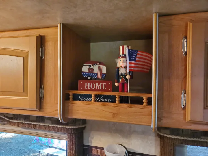 Cozy RV rental interior with patriotic 'Sweet Home' decor, featuring a nutcracker and camper on a wooden shelf.. Forest River Wildcat 2009