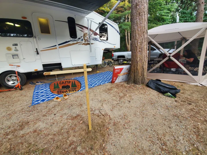 Enjoying an RV rental campsite with a fifth-wheel trailer, pop-up tent, and a "Camp Stearns" sign.. Forest River Wildcat 2009