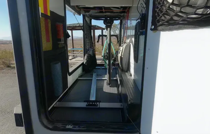 This RV rental's organized interior shows a bike mounted on a track, plus adventure gear storage.. WINNEBAGO EKKO 2023