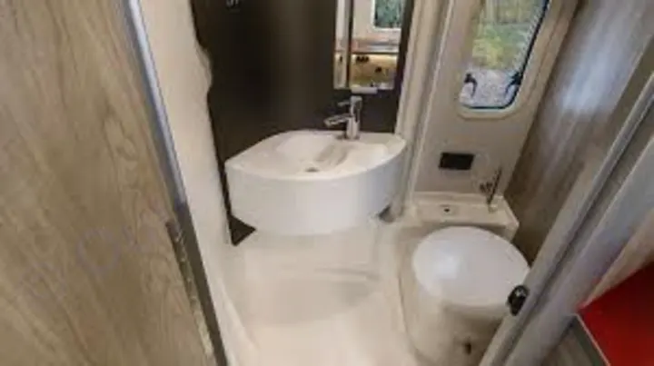 RV rental compact bathroom: Features a white toilet, a curved wall-mounted sink, and a chrome faucet.. WINNEBAGO EKKO 2023