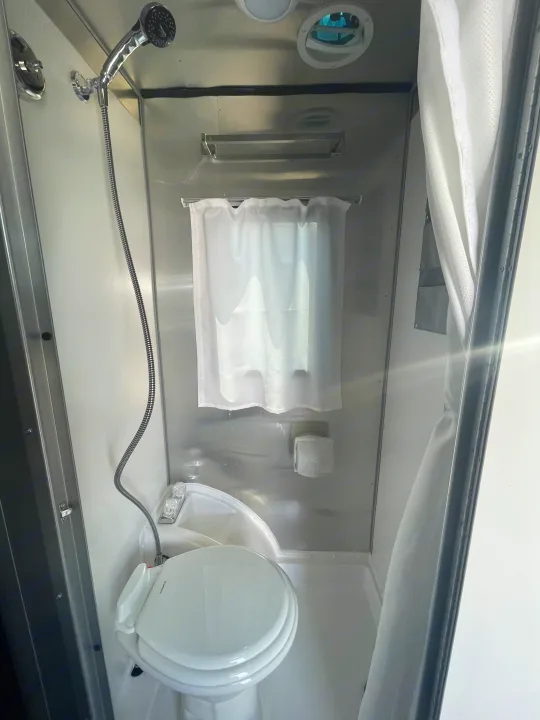 This RV rental wet bath includes a compact toilet, sink, and handheld shower for efficient use during travel.. Airstream Basecamp 2022