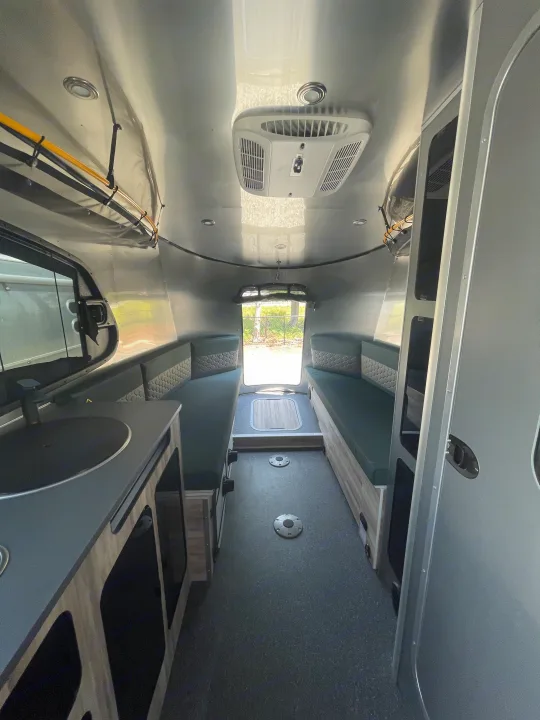 Step inside this cozy RV rental! Features include comfy convertible benches, a small kitchen, and polished aluminum interior.. Airstream Basecamp 2022