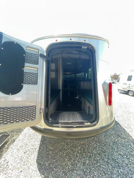Open rear door of an RV rental, revealing its functional interior with twin benches, a central table, and door storage pockets. Great for camper adventures.. Airstream Basecamp 2022
