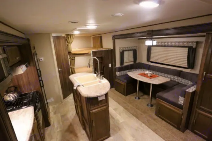 Spacious rv rental interior with kitchen island, U-shaped dinette, and bunk beds. Perfect for family adventures.. Coachmen Apex 2017