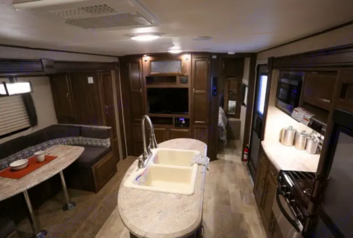 Explore this RV rental's cozy interior with full kitchen, dining booth, and TV area.. Coachmen Apex 2017