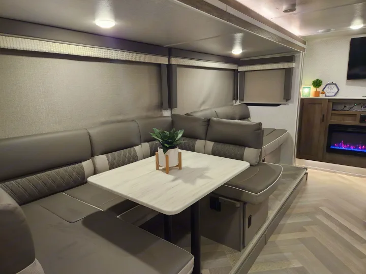 Modern RV rental interior with comfortable dinette seating, herringbone floors, and an electric fireplace.. Forest River Salem Cruise Lite 2022