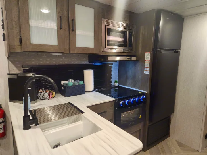 This rv rental features a modern kitchen with microwave, stove, fridge, and sink for comfortable travel.. Forest River Salem Cruise Lite 2022
