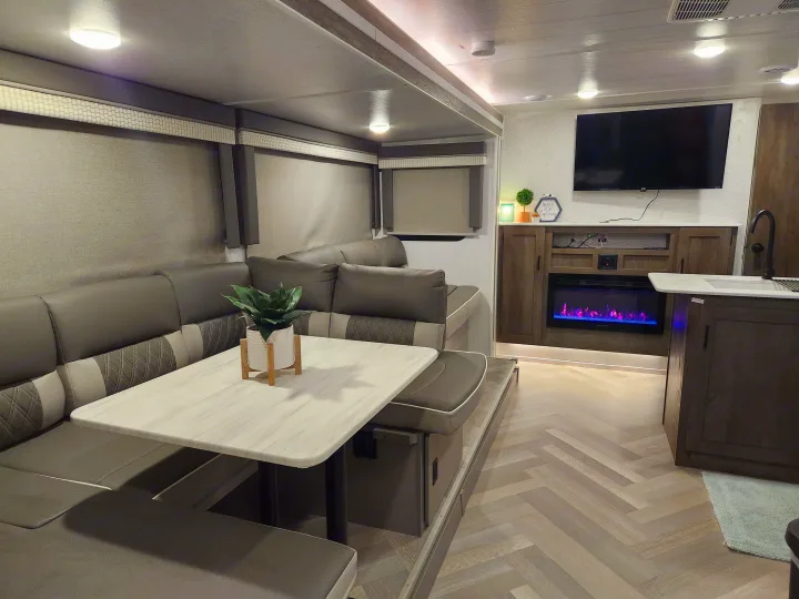 Inside a stylish rv rental: a modern dinette, comfortable seating, TV, electric fireplace, & sleek kitchen. Perfect for trips!. Forest River Salem Cruise Lite 2022