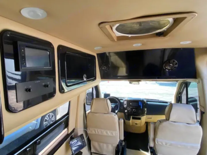Spacious rv rental van interior: cream seating, entertainment system, and overhead storage. Perfect for luxury road trips.. Mercedes Sprinter 2015