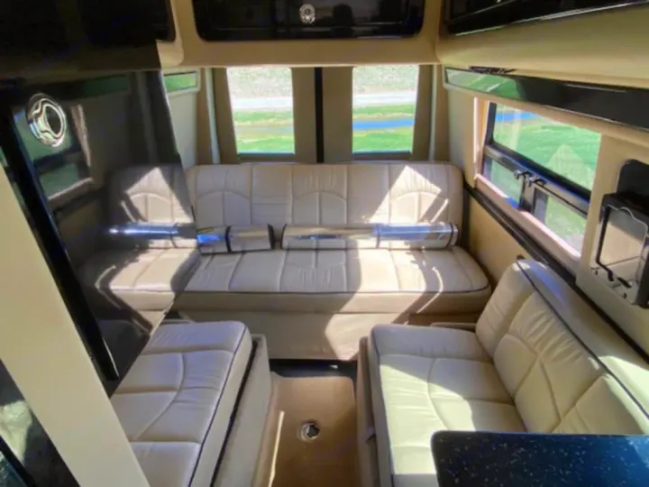 Spacious RV rental interior featuring comfortable, light-colored seating, wide windows with views, and dark modern accents.. Mercedes Sprinter 2015