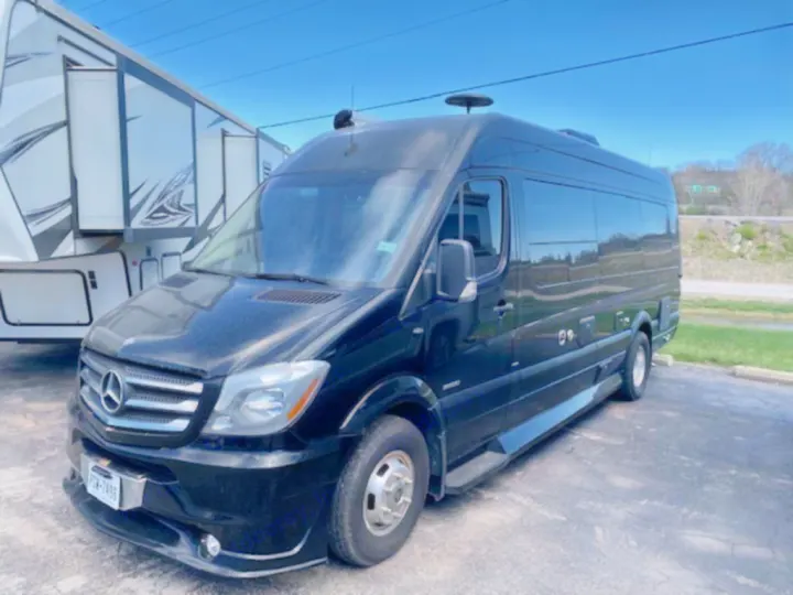 Black Mercedes-Benz Sprinter van, ideal as an RV rental, parked next to a large white fifth-wheel trailer.. Mercedes Sprinter 2015