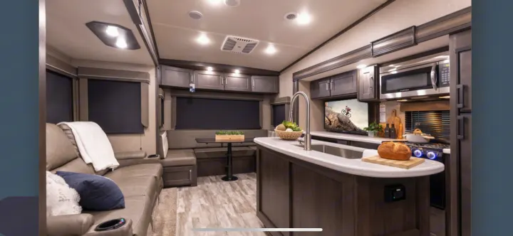 Spacious RV rental interior: modern kitchen with island, comfortable sofa, and dining booth. Ideal for travel adventures.. Grand Design Reflection 2022