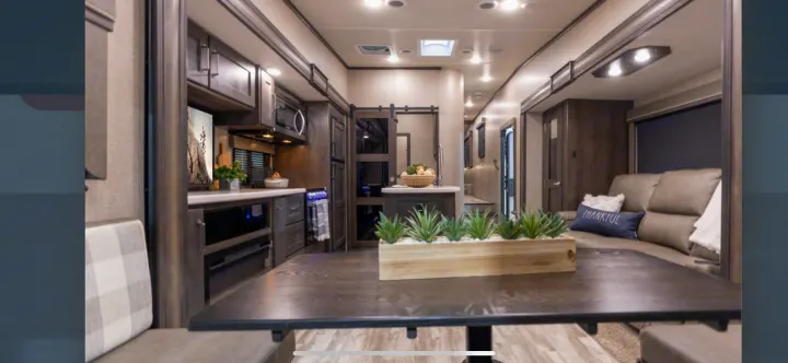 Cozy RV rental interior with a modern kitchen, sofa, and dining table. Perfect for your next adventure on the road.. Grand Design Reflection 2022